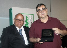 Dr. Alexandre Firmo de Souza Cruz, vice-presidente do Centro Médico, entrega ao Profº João Mazzoncini de Azevedo Marques, filho da Profª Marisa Manzzoncini de Azevedo Marques,  o cartão de homenagem