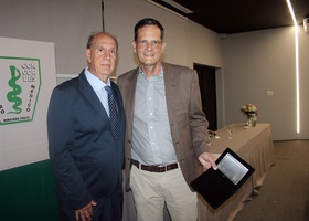 Dr. Ângelo do Carmo Silva Matthes, Conselheiro do Centro Médico, entrega  a José Dutra de Oliveira Neto, filho do Profº Dr. José Eduardo Dutra de Oliveira, o cartão de homenagem In Memoriam